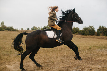 Woman Riding a Black Horse Across a Scenic Open Field
