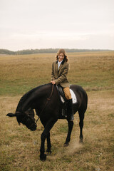 Woman Riding a Black Horse in a Scenic Outdoor Meadow