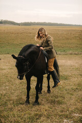 Woman Horseback Riding in Open Field with Black Horse in Autumn