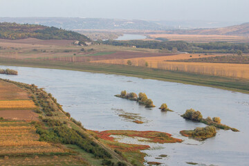 Expansive river landscape with agricultural fields, small islands, and distant hills, perfect for...