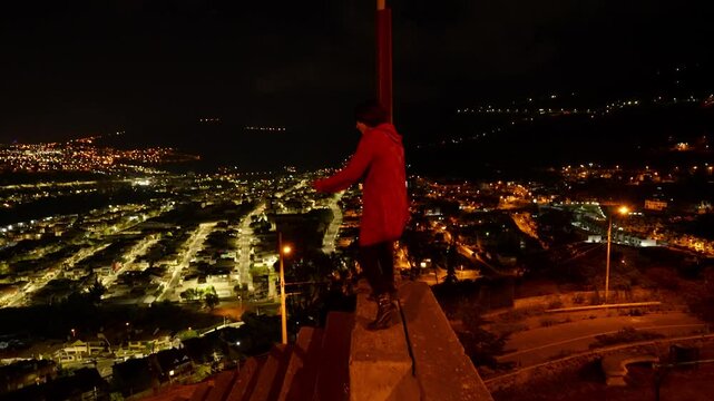 Stylish woman walking confidently on historic monument, featuring illuminated Ambato cityscape and urban nighttime landscape of Ecuador after sunset