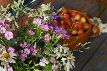 A bouquet of wild flowers against the background of ripe cherries - the concept of a vitamin summer