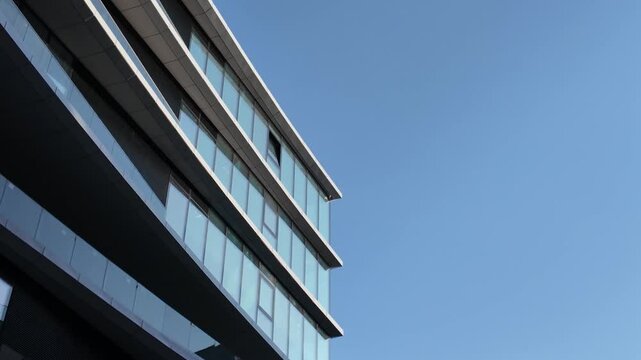 Upward view of a contemporary building in Vilnius featuring metallic cladding and reflective glass windows under a clear blue sky.