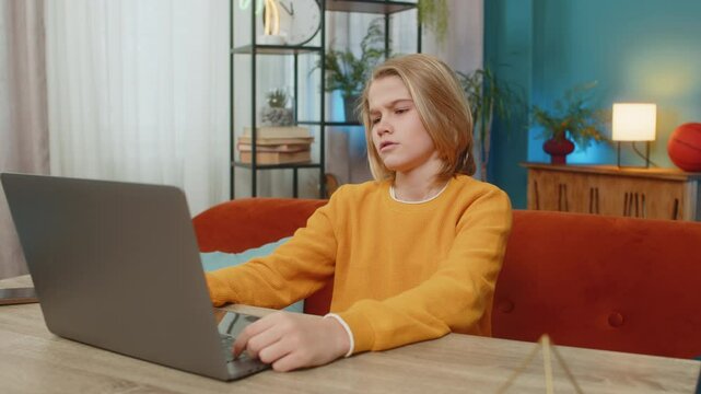 Caucasian teenager boy receiving bad news on laptop at home. Seeing poor education exam results negative grades at school, sitting gloomily on couch by table, looking at screen with sad expression