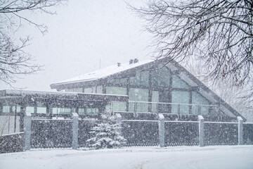 Winter weather scene with country house in heavy snowfall, cold season concept.