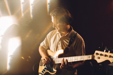Musician playing bass guitar in recording studio with warm lighting