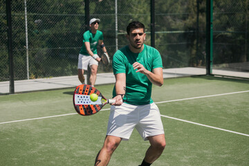 Two padel players with racket on court in action at tournament