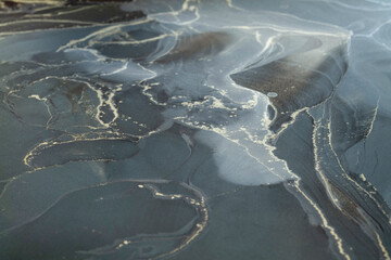 Abstract artwork created with alcohol ink on a textured surface showcasing fluid patterns