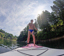 Tourist on a stand up paddle board in the lake of Piazze in Trentino, Northern Italy. The man is...