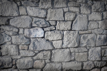 Rustic Grey Stone Wall Texture Background. A close-up of a rustic stone wall featuring irregularly...