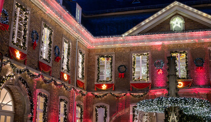 A historic old town house in Cologne at night, adorned with festive Christmas lights and decorations on the windows, roofs and brick walls.