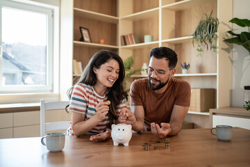 Happy couple saving money together in piggy bank at home