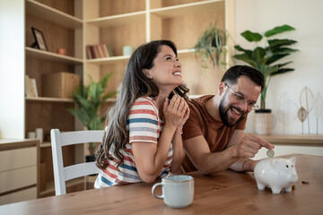 Happy couple saving money together in piggy bank at home