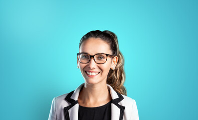 High quality portrait of young woman with tied hair smiling looking at camera on blue background