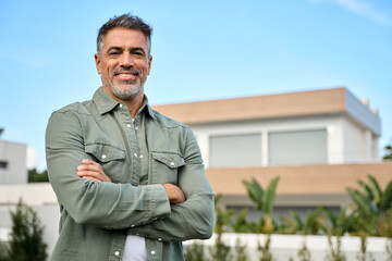Smiling middle aged homeowner, happy mature older Latin man new property buyer modern villa owner...