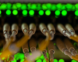 Close-up view of fiber optic cables plugged into a network switch, with green LED status lights...