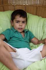 Relaxed Young Boy in Green Shirt Sitting in Chair 