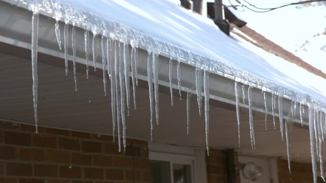 Ice crystals melting on gutters of home slow motion