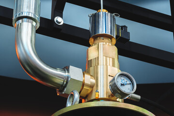 Detailed view of a brass pressure regulator in a modern industrial setting during daylight hours