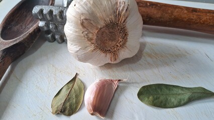 Garlic bulb, clove, and bay leaves on a cutting board
