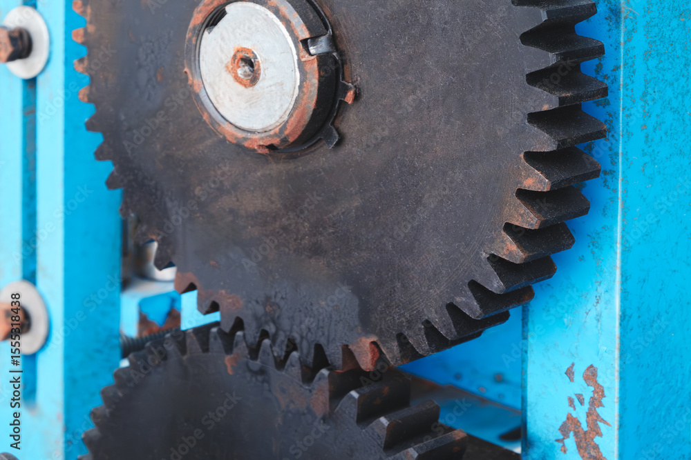 Aufkleber blue machine with two black gears. the gears are rusty and worn. the machine is old and has a vintag