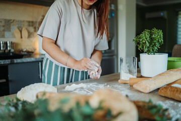 Young caucasian woman making bread dough with rolling pin and flour	
