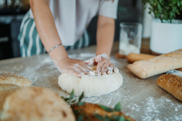 Young caucasian woman making bread dough with rolling pin and flour	
