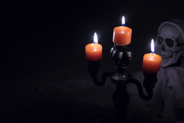Orange Candles Burning in Front of Skeleton in Dark Halloween Scene
