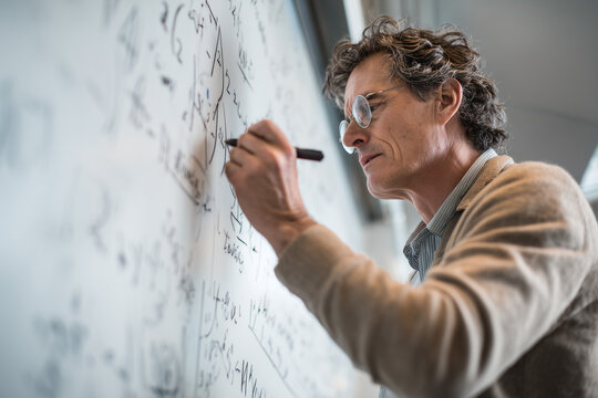 Professor writing equations: a focused professor at the whiteboard - Powered by Adobe