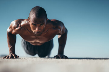 Intense athlete workout: focused male athlete doing push-ups outdoors