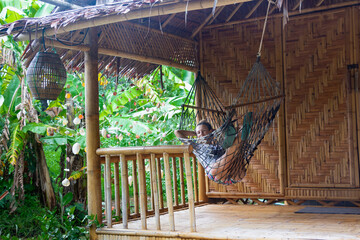 Vacation in Thailand in bugalow. Sea, beach, tropical fruits and drinks. Fit couple in hammock.