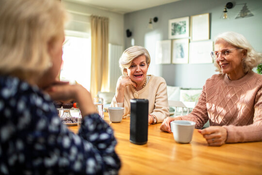 Senior women talking around table with smart speaker and coffee cups