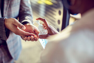 Business professionals using hand sanitizer in office entrance for hygiene and safety