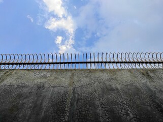Concrete Wall with Iron Barriers Against Blue Sky