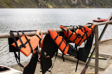 Life jackets in vivid colors hang in a row, sun-drenched and still dripping, after a day of paddling. A quiet scene that captures the pause between adventures in nature.


