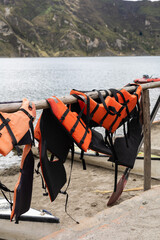 A row of colorful life vests hangs from a simple wooden pole, gently swaying in the breeze. Their presence recalls recent journeys, safety, and the joy of shared adventures.

