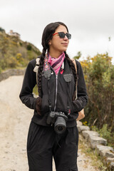 A woman walks along a peaceful dirt trail with her hands in pockets, feeling the cool air. The serene landscape around her adds to the quiet, reflective mood of the moment.

