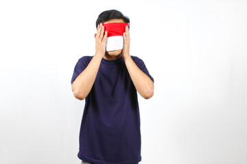 Asian man covers his face with red and white flag as a sign of love celebrating Indonesian...