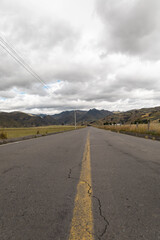 A quiet country road winds between wide green fields under a clear blue sky. The peaceful setting...