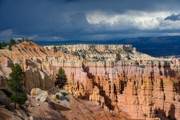 Stunning landscape in rock with pink, orange, and tan hoodoos below a stormy sky, summer vacation exploring in Bryce Canyon National Park, Utah+
