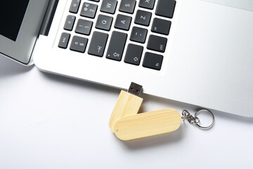 Modern laptop with wooden USB flash drive isolated on white background