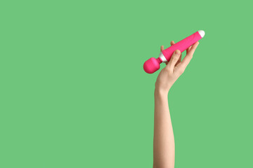 Woman with pink vibrator from sex shop on green background