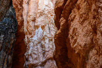 View of light colored rock through a slot canyon of darker orange rock, summer vacation exploring in Bryce Canyon National Park, Utah
