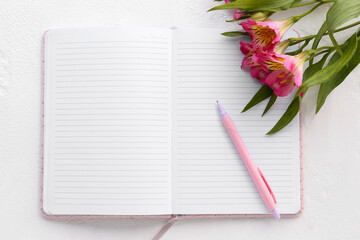 Naklejka premium Blank open notebook with pen and alstroemeria flowers on light background