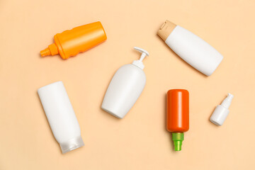 Different bottles of sunscreen cream on pale orange background