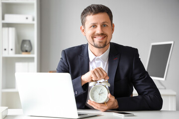 Young businessman with alarm clock in office