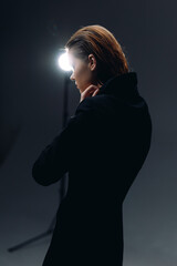Profile of a thoughtful woman with braided hair wearing a black outfit, illuminated by a bright...