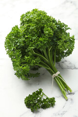 Bunch of fresh parsley on white marble table, closeup