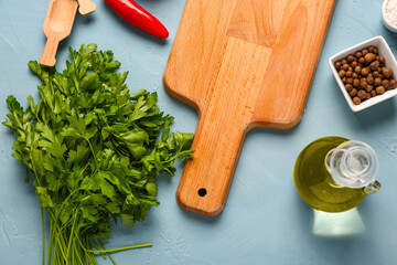 Wooden cutting board and aromatic spices on color background
