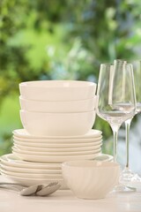 Different clean dishes on white table against blurred green background